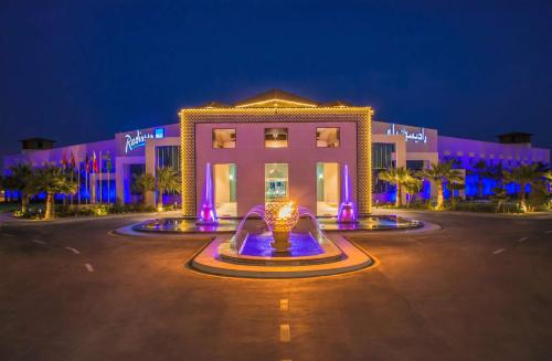 un edificio con una fuente delante de él por la noche en Radisson Blu Resort, Al Khobar Half Moon Bay, en Bahía de la Media Luna