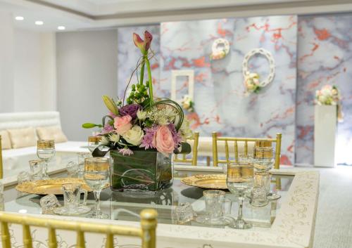 a table with a vase of flowers and glasses at Park Inn by Radisson Jubail Industrial City in Al Jubail