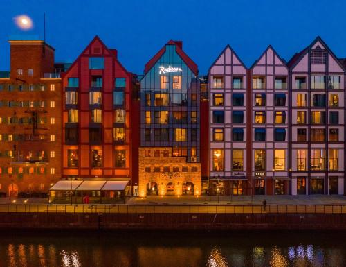 a row of colorful buildings next to a river at Radisson Hotel & Suites, Gdansk, Wyspa Spichrzów in Gdańsk