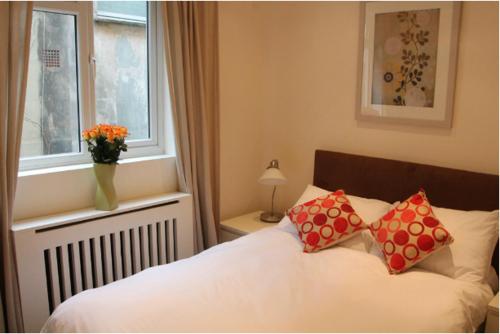 um quarto com uma cama com duas almofadas e uma janela em Oxbridge Apartments em Londres