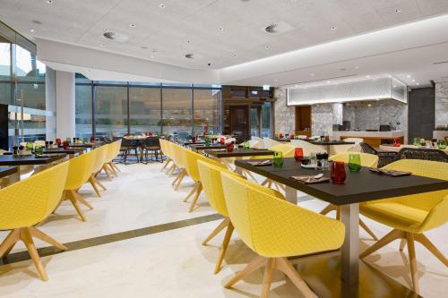 a dining room with tables and yellow chairs at Radisson Blu Hotel & Residence, Riyadh Diplomatic Quarter in Riyadh