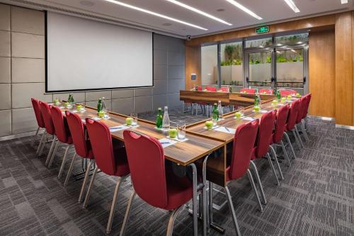 a conference room with a long table and red chairs at Radisson Blu Hotel & Residence, Riyadh Diplomatic Quarter in Riyadh