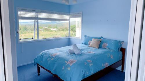 Dormitorio azul con cama y ventana en Panoramic View Apartment Without a Kitchen en Rotorua