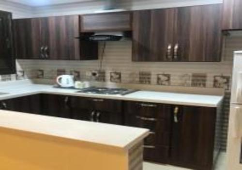 a kitchen with wooden cabinets and a stove top oven at Ashbilia Suites in Al Khobar