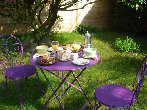 uma mesa roxa com comida na relva em Chambre d'hôte La Bacotterie em Bois-le-Roi