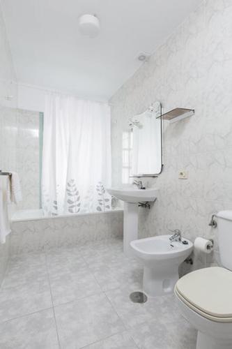 a white bathroom with a toilet and a sink at Pensión Dorotea in Lavacolla