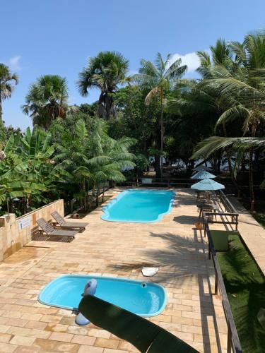 two swimming pools with lounge chairs and palm trees at Pousada Do Rio Barreirinhas in Barreirinhas