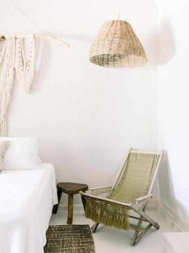 a rattan chair in a bedroom with a bed and a lamp at NEST Tulum in Tulum