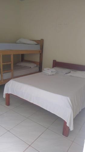 a bed with a white blanket on it in a room at Pousada Potiguara Irapuan in Iranduba