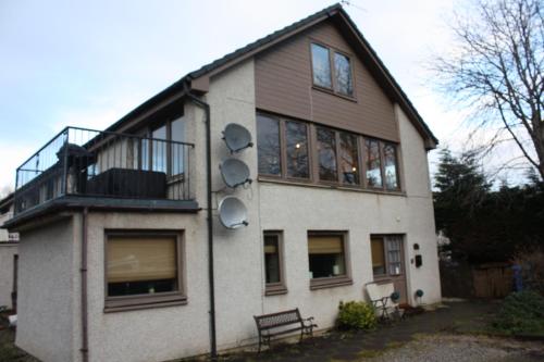 a house with a balcony on the side of it at Loch Ness Balcony Apartment in Drumnadrochit