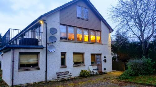 a white house with a balcony on the side of it at Loch Ness Balcony Apartment in Drumnadrochit
