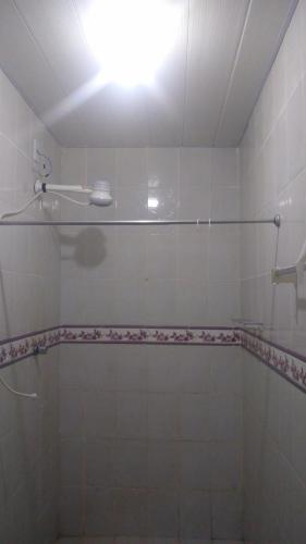 a white tiled bathroom with a shower and a light at Pousada Potiguara Irapuan in Iranduba