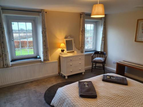 una camera con un letto e una televisione e due finestre di Lovely Cottage on Hadrians Wall 12 Miles From Carlisle a Carlisle