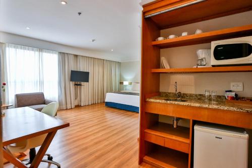 Habitación de hotel con cocina y dormitorio en eSuites Sorocaba by Atlantica en Sorocaba