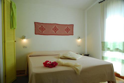 a bedroom with a bed with a red flower on it at Is Cannisonis in Torre Dei Corsari
