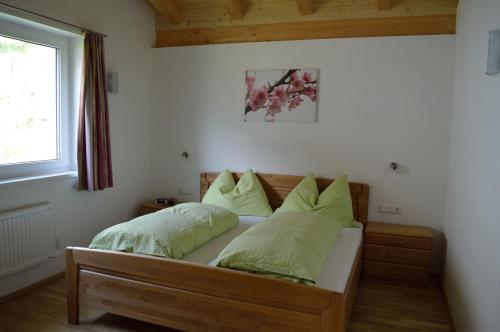 Un dormitorio con una cama con almohadas verdes y una ventana en Haus Klein Rosental, en Neukirchen am Großvenediger