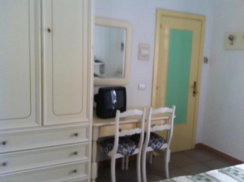 a bedroom with a dresser and a desk with two chairs at Hotel Castiglione in Ischia