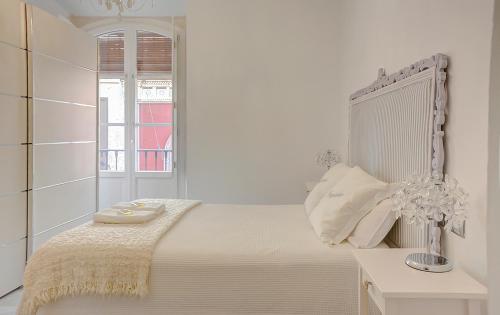 a white bedroom with a bed and a window at Apartamento Trajano in Seville