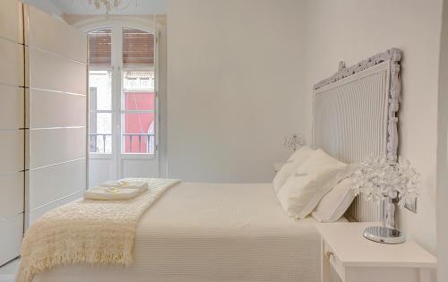 een witte slaapkamer met een bed en een raam bij Apartamento Trajano in Sevilla
