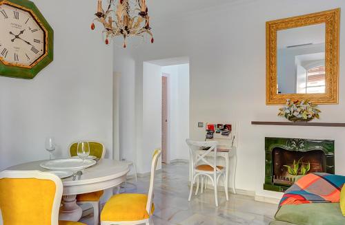 sala de estar con reloj, mesa y sillas en Apartamento Trajano, en Sevilla