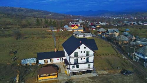 a large white house with a black roof in a field at Pensiunea Vraja in Giuleşti