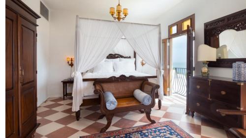 a bedroom with a canopy bed and a chair at THE VILLAS at THE HORNED DORSET PRIMAVERA in Rincon