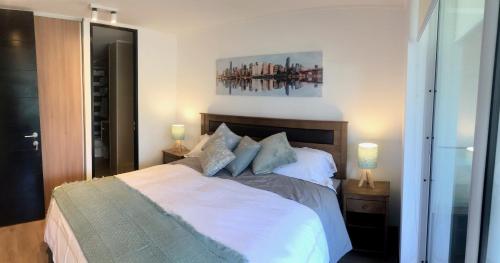 a bedroom with a bed with white sheets and two lamps at Agradable Depto. mirando a Clínica Las Condes in Santiago