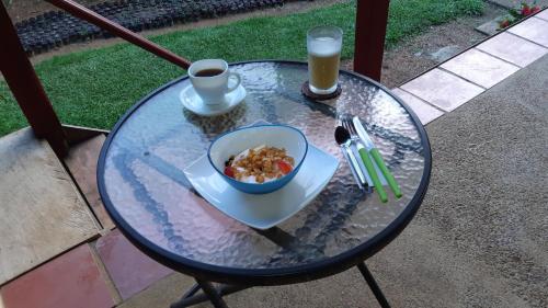 a glass table with a bowl of food and a cup of coffee at Posada turística Quenari Wii in Mitú