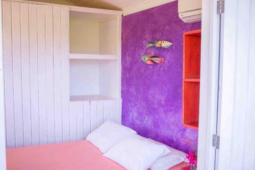 a small bedroom with purple walls and a bed at Stay Cool Pipa in Pipa