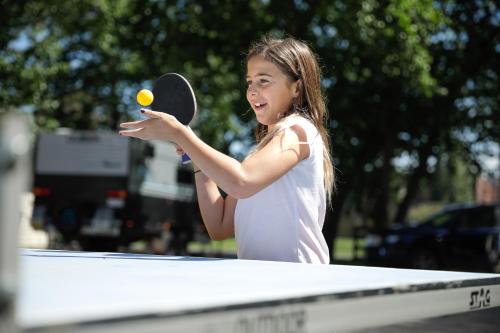 a young girl hitting a tennis ball with a racket at Barwon River Holiday Park in Geelong