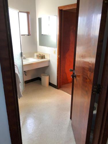 a bathroom with a sink and a mirror and a door at Curly Redwood Lodge in Crescent City