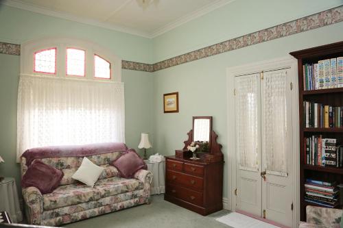 a living room with a couch and a book shelf at Forgandenny House B&B in Mudgee