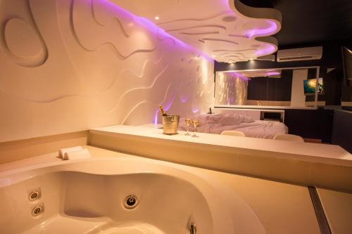 a bathroom with a bath tub and a sink at Tout Motel (Adults Only) in Campinas