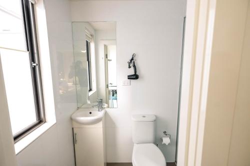 a white bathroom with a toilet and a sink at YHA Melbourne Central in Melbourne