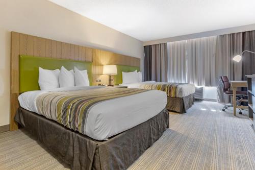 a hotel room with two beds and a desk at Country Inn & Suites by Radisson, Lumberton, NC in Lumberton
