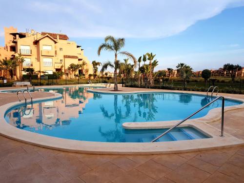 ein großer Swimmingpool mit Bäumen und Gebäuden im Hintergrund in der Unterkunft Casa Colin - Mar Menor Golf Resort in Torre-Pacheco