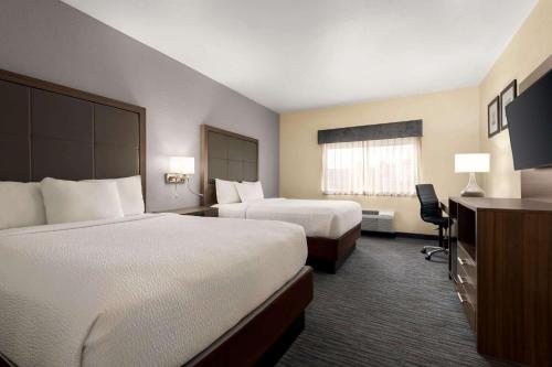 a hotel room with two beds and a desk at Wingate by Wyndham Appleton in Appleton
