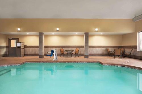 a pool in a hotel room with chairs and tables at La Quinta by Wyndham Lackawanna in Lackawanna