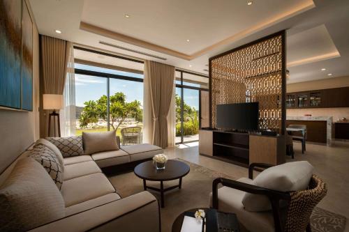 a living room with a couch and a tv at Wyndham Grand KN Paradise Cam Ranh in Cam Ranh