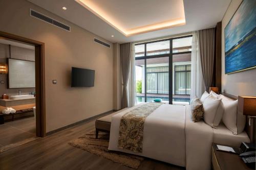 a bedroom with a large bed and a large window at Wyndham Grand KN Paradise Cam Ranh in Cam Ranh