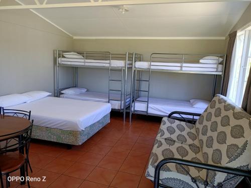 a room with two bunk beds and a table and chairs at Whanganui Seaside Holiday Park in Whanganui