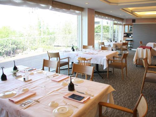 a restaurant with white tables and chairs and a large window at Auberge de South Terrace in Shirahama