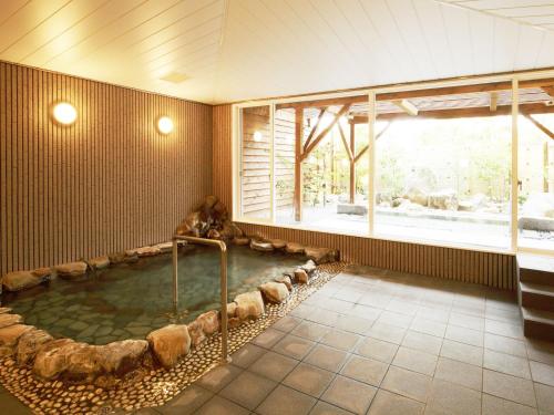 a hot tub in a room with a large window at Auberge de South Terrace in Shirahama