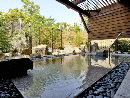 a swimming pool in a backyard with rocks and a house at Auberge de South Terrace in Shirahama