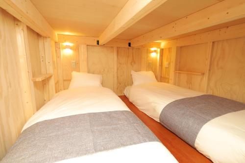 two beds in a small room with wooden walls at JR Mobile Inn Sapporo kotoni in Sapporo