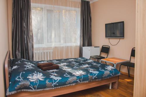 a bedroom with a bed and a tv and a window at Hotel Tahar in Almaty