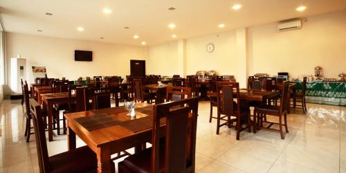 a dining room with wooden tables and chairs at Syariah Arini Hotel in Solo