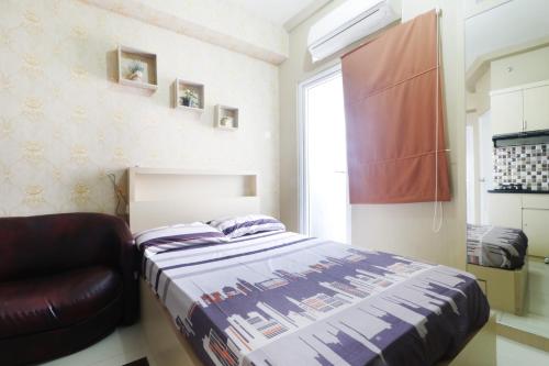 a bedroom with a bed and a chair and a window at Green Pramuka City by SR Property in Jakarta