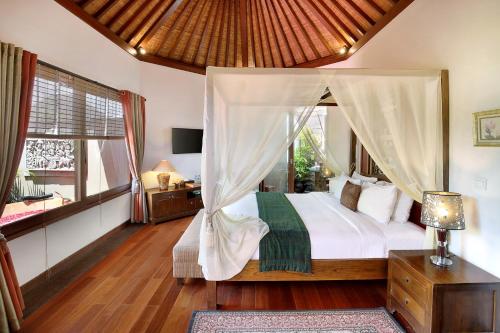 1 dormitorio con cama con dosel y ventana en Kanishka Villas, en Seminyak