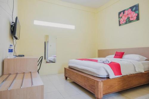 um quarto com uma cama e um banco em RedDoorz near RS Imanuel Lampung em Lampung